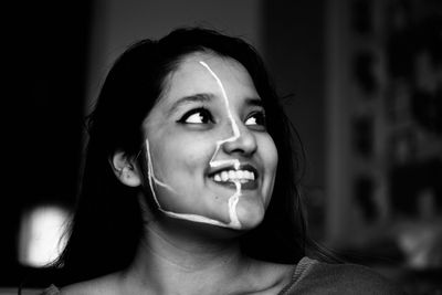Smiling young woman with face paint looking away sitting at home