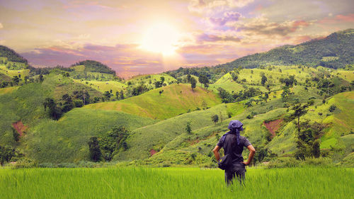 A man standing on the green field under blue sky and sunlight