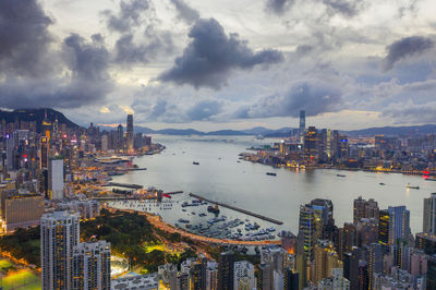 Aerial view of city by bay of water against sky