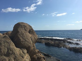 Rock formation on beach against sky