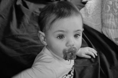 Portrait of cute baby girl sitting on bed at home