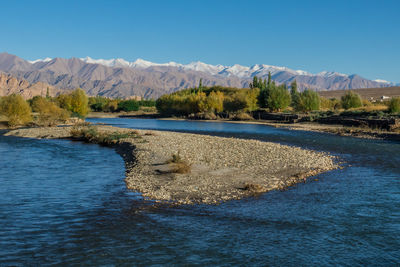 Scenic view of lake and mountains against clear blue sky