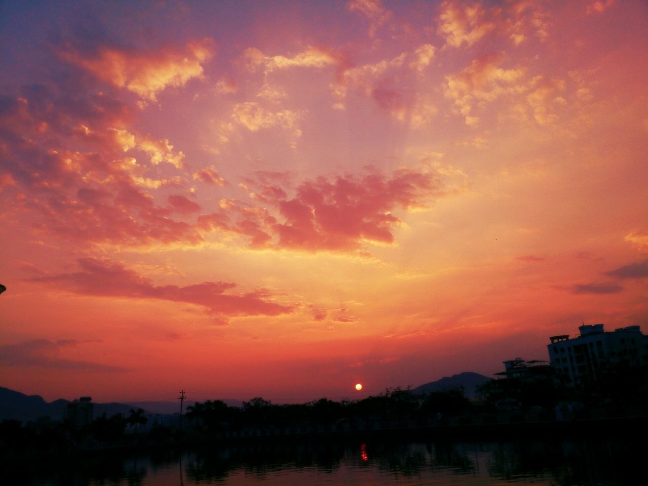 sunset, orange color, sky, silhouette, water, scenics, beauty in nature, tranquil scene, cloud - sky, tranquility, idyllic, waterfront, nature, reflection, dramatic sky, lake, building exterior, cloud, built structure, architecture