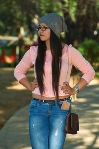 Young woman with hand on hip standing at park