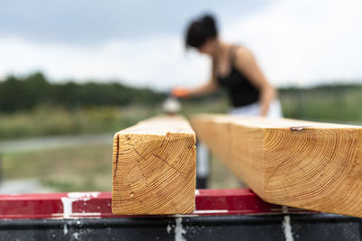 The woman impregnates raw planed wooden pine beams with dimensions of 100x100mm