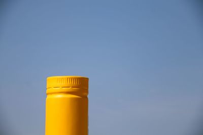 Yellow bottle against clear blue sky