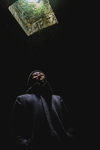 Rear view of man standing against black background