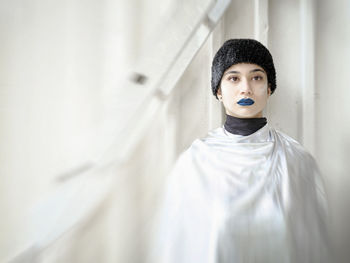 Close-up of young woman standing against wall