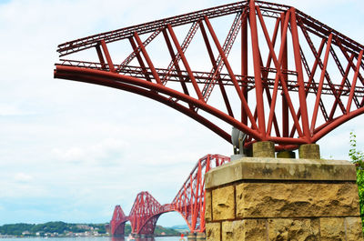 Metal structure by forth bridge against sky