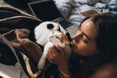 Close-up of woman with cat on bed at home