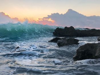 Rock formation on beach against sky during sunset