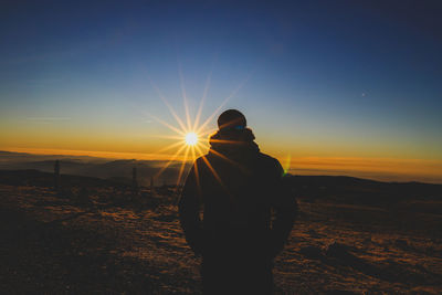 Rear view of man standing against sky during sunset