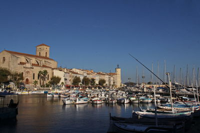 Sailboats moored at harbor against clear blue sky