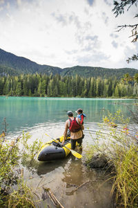 Dad lifts son into inflatable boat in a mountain lake outdoor setting