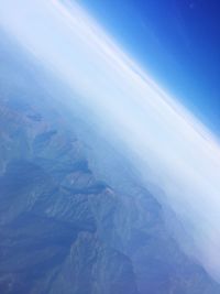 Aerial view of snowcapped landscape against blue sky