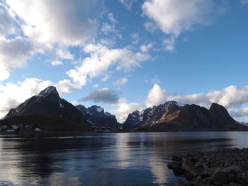 Scenic view of sea and mountains against cloudy sky