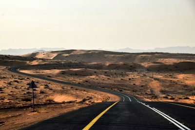 Road passing through desert against sky