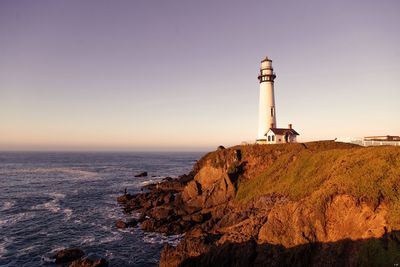 Lighthouse by sea against sky