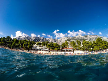 Scenic view of shore by sea against sunny sky