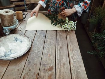 Midsection of woman wrapping flowers at table