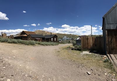 Old houses on field by buildings against sky