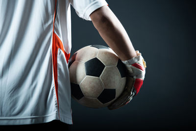 Low section of man playing soccer against black background