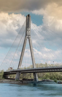 Low angle view of suspension bridge against cloudy sky