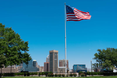 American flag in city against clear blue sky