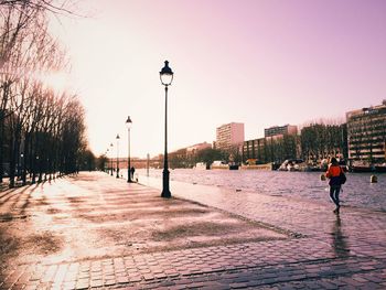 People walking on footpath against clear sky