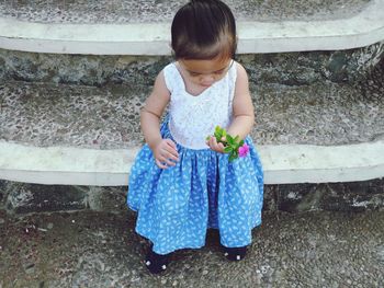 High angle view of cute girl holding flower while standing on steps