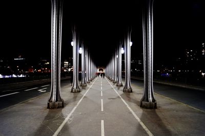 View of illuminated road under bridge in city at night