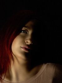 Portrait of young woman against black background