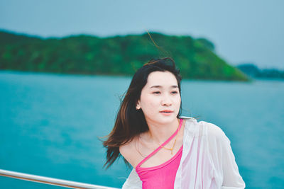 Portrait of young woman standing against sea