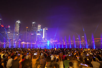 Crowd during music concert against sky at night