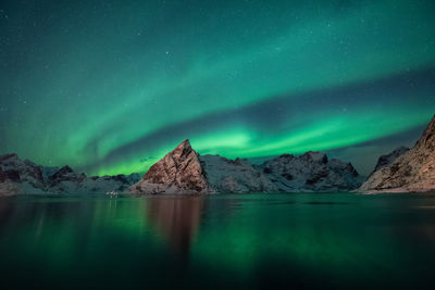 Scenic view of lake and mountains against sky at night