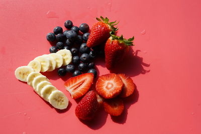 Fresh fruits in plate against red background