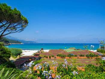 High angle view of townscape by sea against blue sky