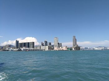 City at waterfront against blue sky