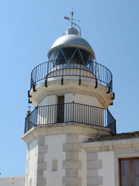 Low angle view of lighthouse on building against clear sky