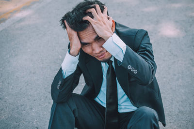 Midsection of a man sitting on street in city