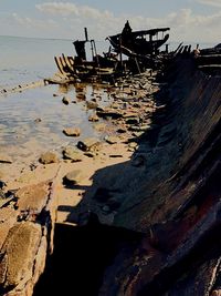 Abandoned boat on beach against sky