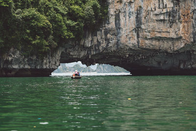 People rowing boat on halong bay under rock formation