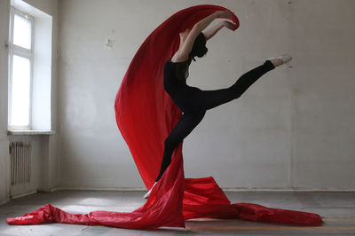 Young woman doing ballet dance with red fabric