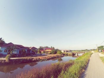 River by houses against clear blue sky