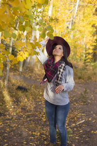 Full length of young woman standing in park during autumn