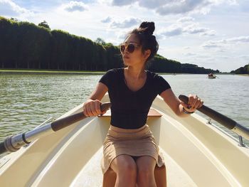 Woman rowing boat in sea against sky