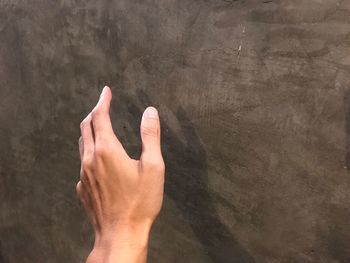 Cropped hand of man reaching towards wall