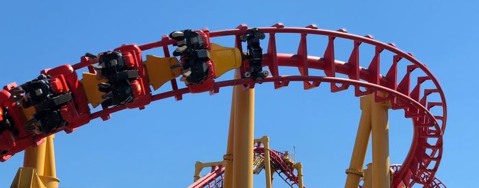 Low angle view of chain swing ride against clear blue sky