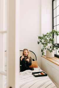 Portrait of young woman sitting on table at home