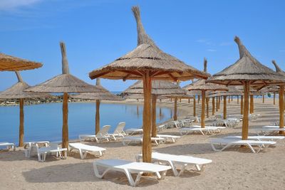 Lounge chairs and parasols on beach against sky